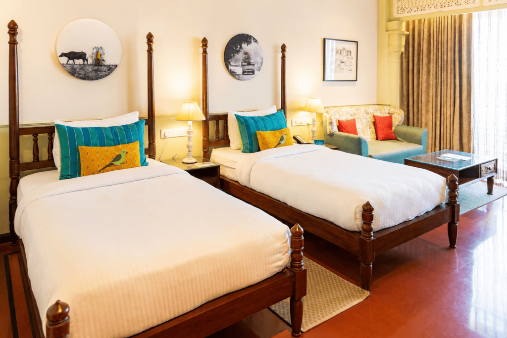 Two twin beds with white linens and wooden frames in a well-lit hotel room with a window view.